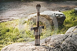 famous sword excalibur of King Arthur stuck in rock. Edged weapons from the legend Pro king Arthur