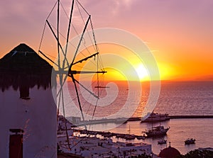 Famous traditional Greek windmill, Mykonos, Greece against sunset and sea. Beautiful sky, sun touch sea horizon