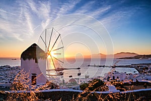 Famous traditional white windmill overlook port and harbor of Mykonos, Cyclades, Greece at sunset sky. Beautiful sky