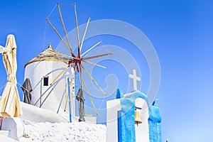Famous Travel places. Picturesque View of Traditional Windmill with Greek Flag in Oia Village in Santorini Island in Greece