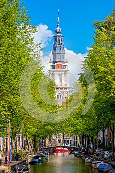 Famous view of Amsterdam -  South Church overlooking the canal and boats and in the shade of trees. Amsterdam, Holland,