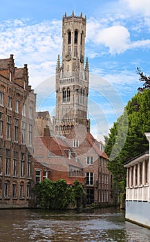 Famous view of Bruges tourist landmark attraction - Rozenhoedkaai canal with Belfry and old houses along canal with tree
