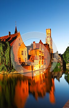 Famous view of Bruges tourist landmark attraction - Rozenhoedkaai canal with Belfry and old houses along canal with tree in the