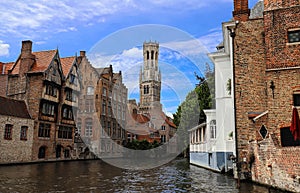 Famous view of Bruges tourist landmark attraction - Rozenhoedkaai canal with Belfry and old houses along canal with tree