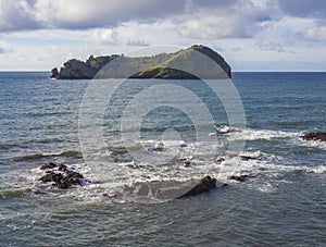 Famous volcanic islet of Vila Franca do Campo, small green crater island near sea shore with rocks ocean, blue sky and