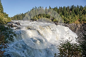 Famous waterfall Tannforsen northern Sweden, with a rainbow in the mist and rapid flowing cascades of water