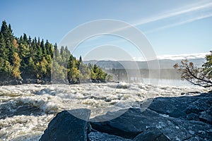 Famous waterfall Tannforsen northern Sweden, with a rainbow in the mist and rapid flowing cascades of water