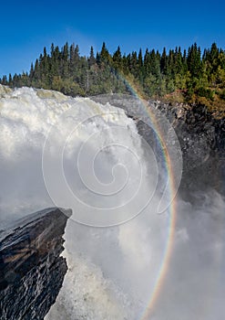 Famous waterfall Tannforsen northern Sweden, with a rainbow in the mist and rapid flowing cascades of water