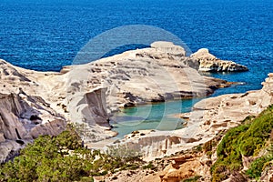 Famous white rocks of Sarakiniko beach, Aegean sea, Milos island , Greece. Few tourist hide in shade, empty cliffs