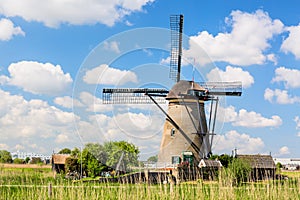 Famous windmills in Kinderdijk village in Holland. Colorful spring rural landscape with windmill and blue cloudy sky in Netherland