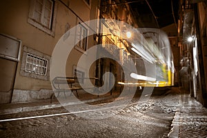 Famous yellow tram 28 in motion blur at night in Lisbon. long exposure of tram in old part of city