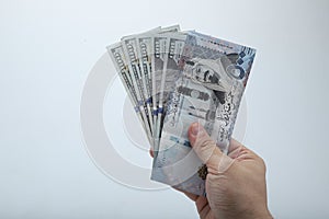 Fan of money  dollar and riyals in male hands isolated on white.