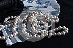 A fan and pearl necklace.