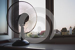 A fan standing on the window sill.