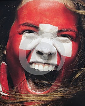 Fan with Swiss flag painted on the face - Stock Photo