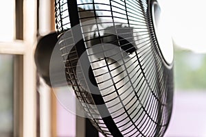 Fan turbine in front of a window. The electric fan slows down and resumes movement