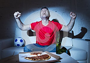 Fanatic football fan man watching soccer game on tv celebrating