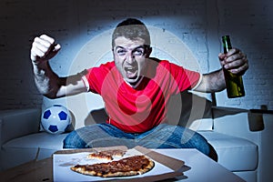 Fanatic football fan man watching soccer game on tv celebrating