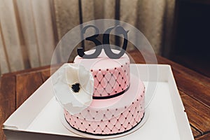 Fancy cake with number 30 candles. Decorated with ribbons and star-shapes, in pastel tones.