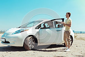 Stylish man wearing beige trousers standing near his new fancy car