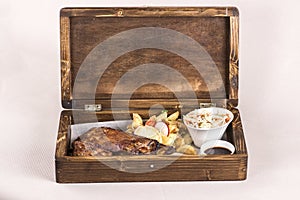 Fancy dish with grilled pork ribs, barbecue sauce, French fries, Coleslaw salad, in a wooden box