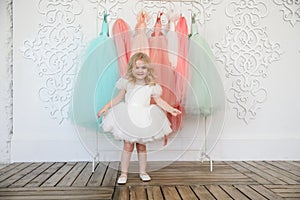 Kid girl in dress near hanger with festive clothes photo
