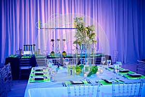 Fancy guest square table set up for a wedding or social event in the ballroom orchid and lucite sitting placement green and red