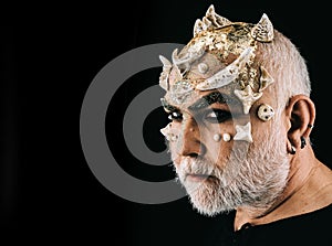 Fancy Halloween make-up, actor portraying ugly monster with thorns on face. Side view bearded man with evil eyes wearing