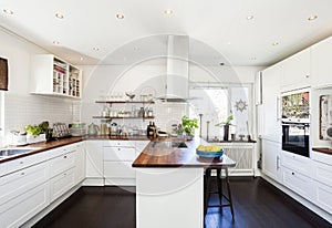 Fancy kitchen interior with wooden counter top and dar wooden floor white cupboards photo