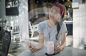 Fancy model in red headscarf and round glasses posing with a phone outdoors