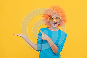 fancy party look. kid in clown wig presenting product. funny child with fancy hair.