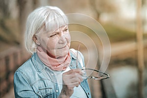 Elegant comely aging missis holding her glasses in a hand