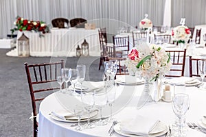 Fancy table set for dinner with flower composition in restaurant, luxury interior background. Wedding elegant banquet