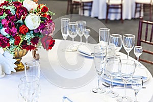 Fancy table set for dinner with flower composition in restaurant, luxury interior background. Wedding elegant banquet