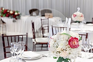 Fancy table set for dinner with flower composition in restaurant, luxury interior background. Wedding elegant banquet decoration