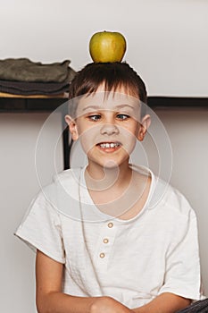 Fanny boy in the kitchen with a green apple. Healthy food for children concept