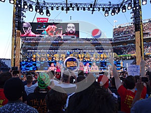 Fans cheer as WWE Wrestler John Cena enters the stadium with Rusev stands in ring holding USA Championship title
