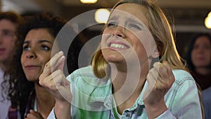 Fans emotionally cheering for sports team victory watching football match in bar