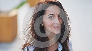 Fantasic brown-eyed and brown-haired caucasian girl ardently looking in the camera and smiling, portrait with urban