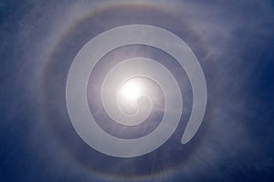 Fantastic beautiful sun halo phenomenon in the blue sky. Rainbow in the form of a circle around the sun.