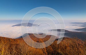 Fantastic and dramatic view of valley covered in dense fog with only mountain tops peaking out of the fog.