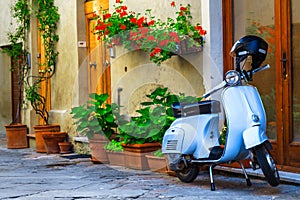 Fantastic Italian street with colorful flowers and scooter, Pienza, Tuscany