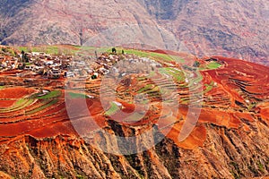 Fantastic landscape, colorful scenic old village of Red Land at sunrise, red mountain backgrounds. The sun shines down around