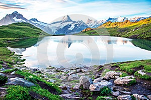 Fantastic landscape at sunrise with stones in the foreground on the lake in the Swiss Alps. Wetterhorn, Schreckhorn,
