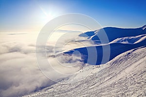 Fantastic scenery with the high mountains in snow, dense textured fog in the cold winter day. Winter landscape with fog.