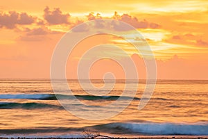 Fantastic scenic seascape at dusk, colorful sunset sky with clouds in summertime. A soft orange glow blankets the sky as gently