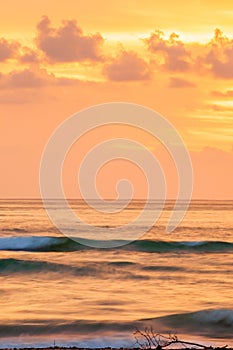 Fantastic scenic seascape at dusk, colorful sunset sky with clouds in summertime. A soft orange glow blankets the sky as gently