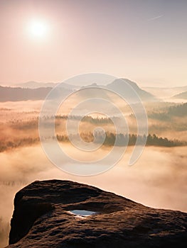 Fantastic sunrise on the top of the rocky mountain with the view into misty valley