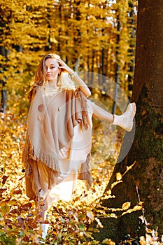 A fantastic woman in the autumn forest on the background of yellow cast threw her leg on a tree. Practically vertical twine