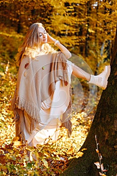 A fantastic woman in the autumn forest on the background of yellow cast threw her leg on a tree. Practically vertical twine